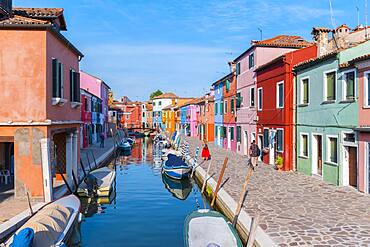 Young woman in front of colorful houses, canal with boats and colorful house facades, Burano Island, Venice, Veneto, Italy, Europe