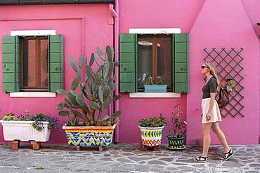 Young woman in front of colorful house, pink house facade, tourist on Burano island, Venice, Veneto, Italy, Europe