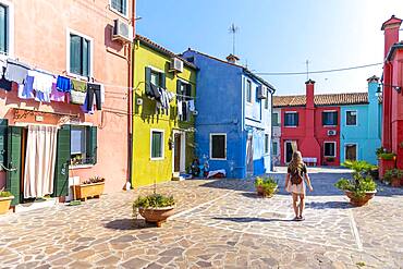 Young woman in front of colorful houses, colorful house facades, Burano Island, Venice, Veneto, Italy, Europe