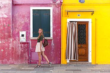 Young woman in front of colorful house, colorful house facades, tourist on Burano island, Venice, Veneto, Italy, Europe