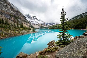 Clouds hanging between mountain peaks, reflection in turquoise glacial lake, Moraine Lake, Valley of the Ten Peaks, Rocky Mountains, Banff National Park, Alberta Province, Canada, North America