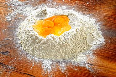 Flour with eggs on wooden table, Germany, Europe