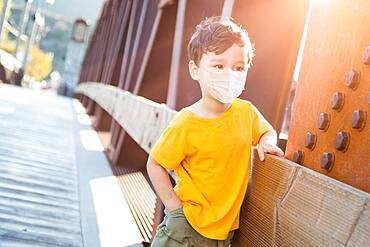 Young Mixed Race Chinese and Caucasian Boy Playing Alone Wearing Medical Face Mask Outside