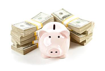 Pink piggy bank with stacks of hundreds of dollars isolated on a white background