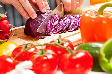 Man slicing vegetables on wooden cutting board