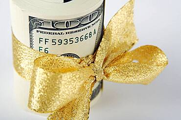 One hundred dollar bills wrapped in gold ribbon