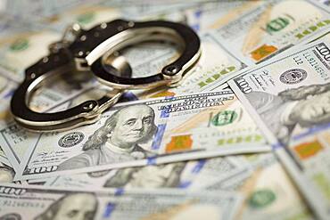 Handcuffs laying on newly designed U.S. one hundred dollar bills