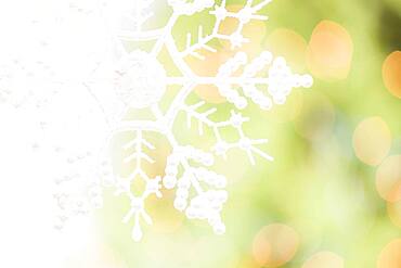 White glittery snowflake over an abstract green and gold background