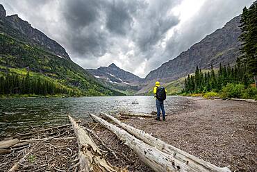 Hikers at Upper Two Medicine Lake, mountain peaks Lone Walker Mountain and Mount Rockwell in the background, dramatic clouds, Glacier National Park, Montana, USA, North America