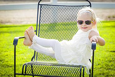 Cute playful baby girl wearing sunglasses outside at the park