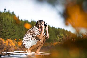 Guy with camera on car roof, Rotorua, Bay of Plenty, North Island, New Zealand, Oceania