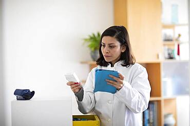 Pharmacist with medicine in a pharmacy working with modern technology and smock, Freiburg, BW