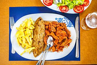 Traditional food from Alentejo, cow's tongue in a sauce served with salad, rice and french fries, Portugal, Europe