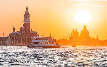 Vaporetto, water bus driving on the lagoon of Venice, evening mood, island Isola di San Giorgio Maggiore with church San Giorgio Maggiore, Basilica Santa Maria della Salute, Venice, Veneto, Italy, Europe