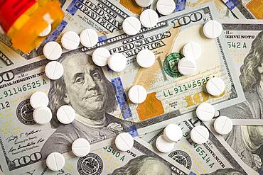 Medicine pills scattered on newly designed U.S. one hundred dollar bills