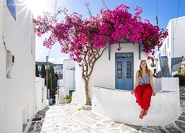 White-blue houses with blooming purple Bougainvillea (Bougainvillea), Young woman with red dress in the old town of Lefkes, Paros, Cyclades, Greece, Europe