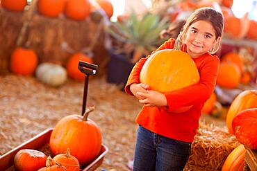 Cute girl choosing A pumpkin at A pumpkin patch one fall day