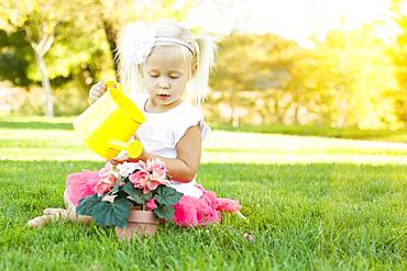 Cute little girl playing gardener with her tools and flower pot