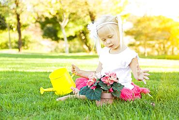 Cute little girl playing gardener with her tools and flower pot