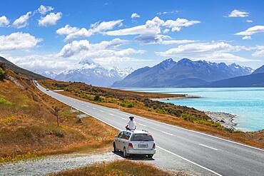 Guy on a car roof, Lake Pukaki, Mount Cook, Canterbury region, Mackenzie District, South Island, New Zealand, Oceania