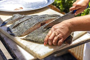 A cook cutting the fish to be barbecued in Portuguese restaurant