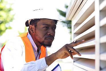 Young black man working outside as technician with helmet and safety vest, Freiburg, Baden-Wuerttemberg, Germany, Europe