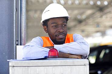 Young black man working outside as technician with helmet and safety vest, Freiburg, Baden-Wuerttemberg, Germany, Europe