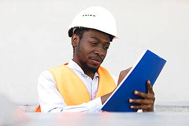 Young black man working outside as technician with helmet and safety vest, Freiburg, Baden-Wuerttemberg, Germany, Europe