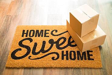 Home sweet home welcome mat on wood floor with shipment of boxes