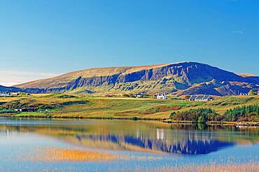 Mountains and houses reflected in a loch, autumn light, Quiraing, Isle of Skye, Hebrides, Scotland, United Kingdom, Europe