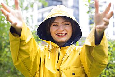 Happy young woman with yellow rain jacket with hood, Baden-Wuerttemberg, Germany, Europe