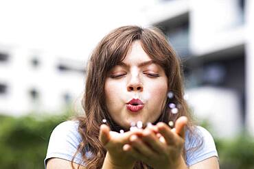 Young woman with long hair blowing into her hands, Germany, Europe