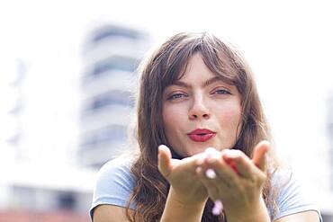 Young woman with long hair blowing into her hands, Baden-Wuerttemberg, Germany, Europe