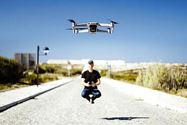 Man holding remote flying together with his drone in first plan