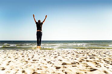 Man jumping on the beach with hands up