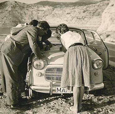 Former People's Republic of Yugoslavia in 1959: young German tourists on a coastal road i, studying a map spread out on the bonnet of their car, Croatia, Europe