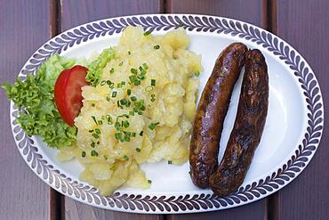 Two Nuremberg bratwursts with potato salad on an oval plate in a garden restaurant, Bavaria, Germany, Europe