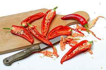 Red sliced peppers on wooden board with knife, Germany, Europe