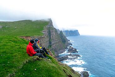 3 Walkers sitting overlooking Beinisforo Cliffs, Sandvik, Suduroy, Faroe Islands, Europe