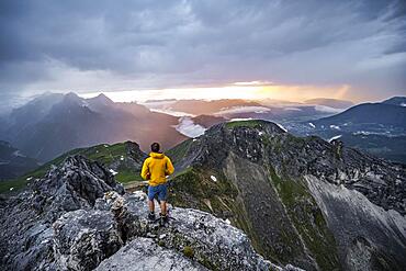 Hikers at the summit of the Westliche Toerlspitze, in the background cloudy mountains at sunset with dramatic light, view of Frauenalpl, Wetterstein Mountains, Garmisch Partenkirchen, Bavaria, Germany, Europe