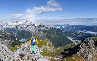 Hiker on a summit, Westliche Toerlspitze, mountains in dramatic clouds, Zugspitze in the back, Wetterstein Mountains, Garmisch-Partenkirchen, Bavaria, Germany, Europe