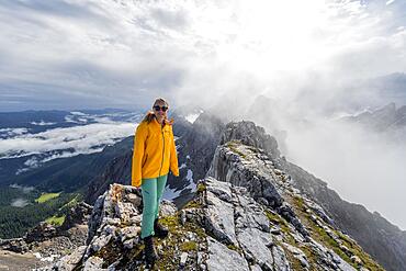 Hiker on a summit, Westliche Toerlspitze, mountains in dramatic clouds, Wetterstein Mountains, Garmisch-Partenkirchen, Bavaria, Germany, Europe