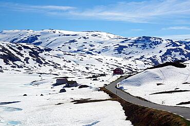 Road winds through wintry landscape in the Fjell, individual mountain huts, Gaularfjellet, Sunndal, Sogndal, Norway, Europe