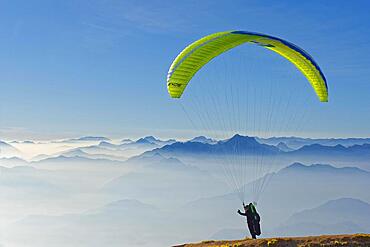 Paraglider taking off with the peaks of the Lake Garda mountains and Bergamo Alps, Monte Baldo, Malcesine, Verona Italy, Trentino-Alto Adige, Italy, Europe