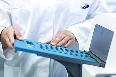 Young laboratory assistant with sample working in a laboratory with laboratory equipment, Freiburg, Baden-Wuerttemberg, Germany, Europe