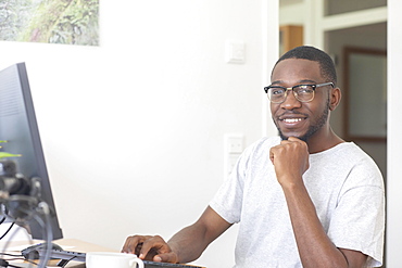 Young black man working at desk in office, Freiburg, Baden-Wuerttemberg, Germany, Europe