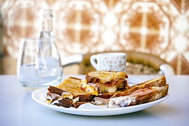 Tasty toasted bread with butter, ham, and cheese served with beverages in Portugal