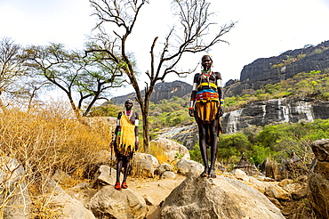 Traditional dressed young girls from the Laarim tribe standing on a rock, Boya hills, Eastern Equatoria, South Sudan, Africa