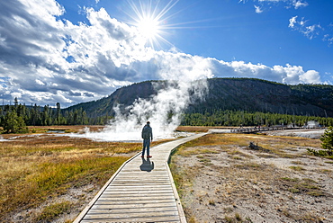 Tourist on a logging road in front of steaming hot spring, Biscuit Basin, Yellowstone National Park, Wyoming, USA, North America