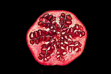 Halved pomegranate (Punica granatum), studio photography with black background